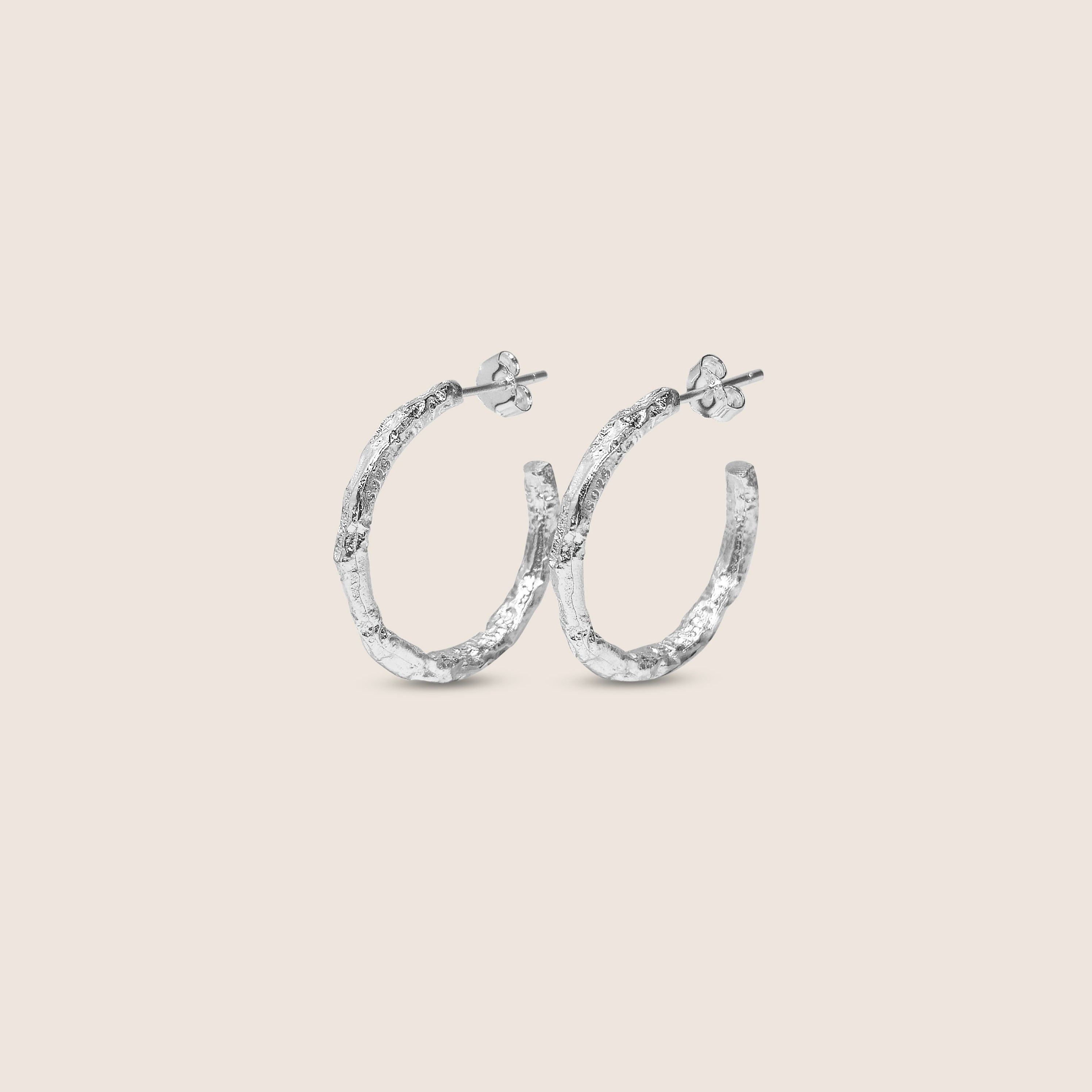 Silver hoop earrings on a light beige background